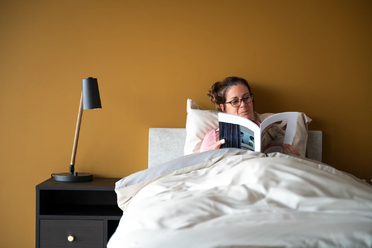 Oudere vrouw leest in 1-persoons seniorenbed