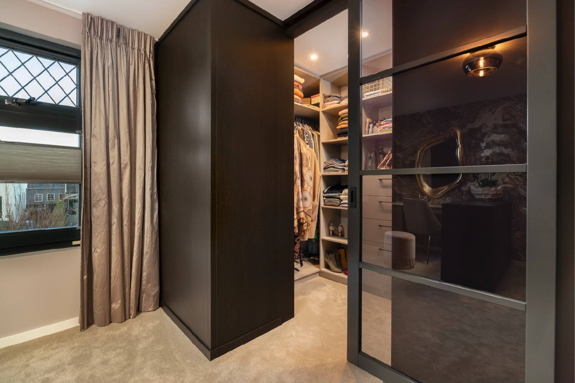 Inloopkast achter bed in hotelchique slaapkamer