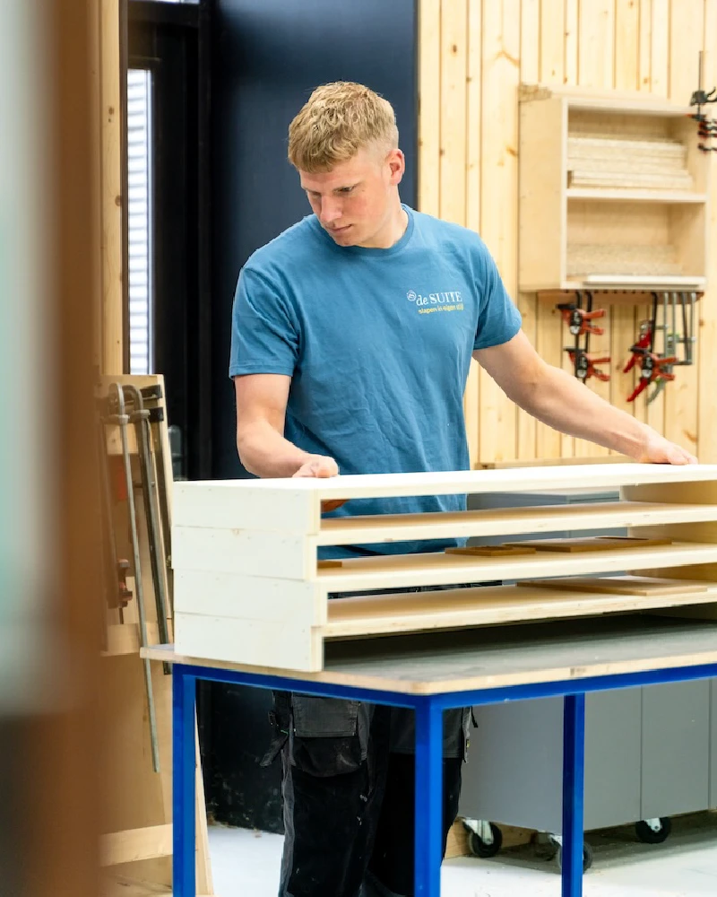 Meubelmaker werkt aan een houten bed in het atelier