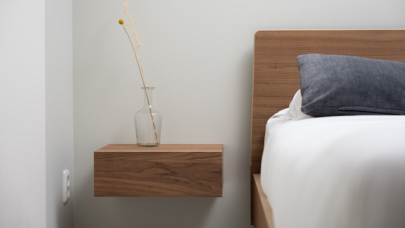 zwevend nachtkastje naast houten design bed