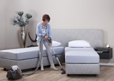 vrouw maakt schoon onder deelbaar hoog laag bed