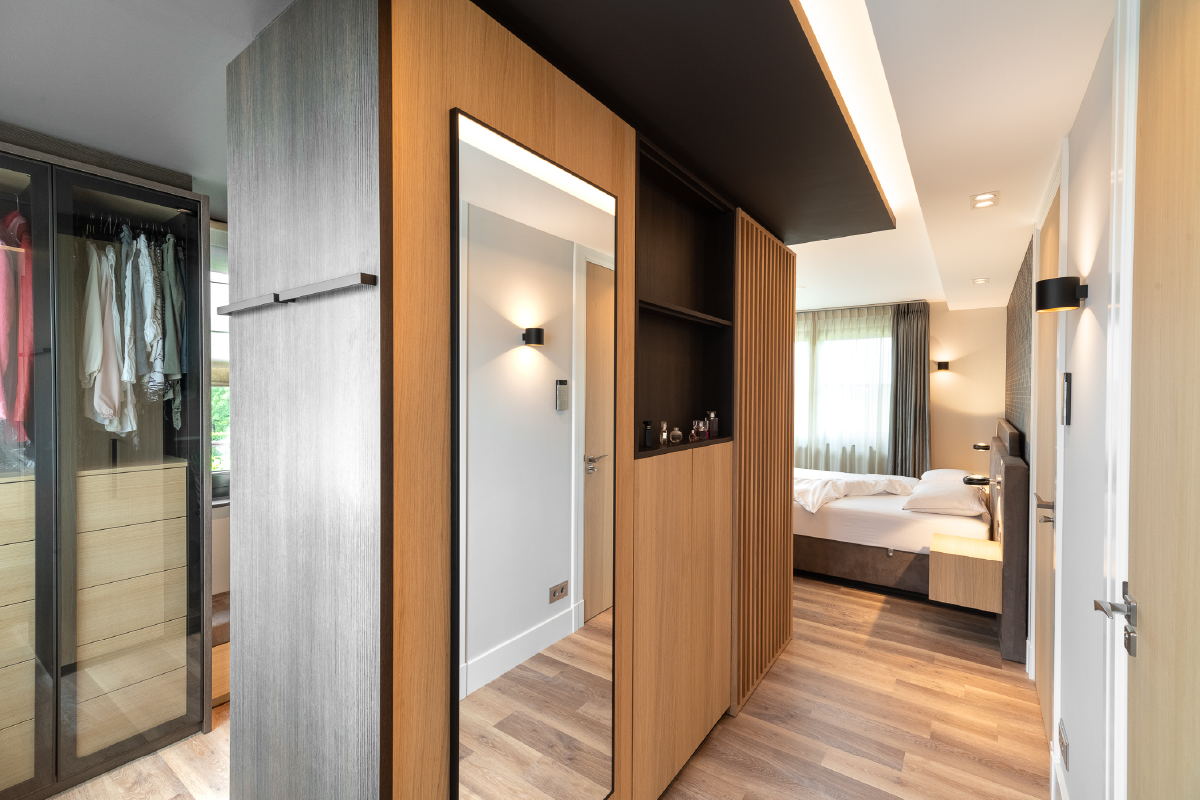 Inloopkast met glazen deuren en grote spiegelwand in hotelchique slaapkamer