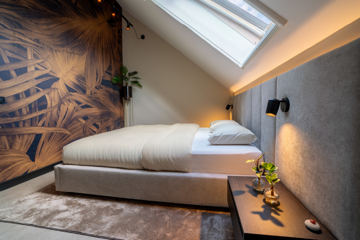 Maatwerk kast onder schuin dak in moderne zolder slaapkamer