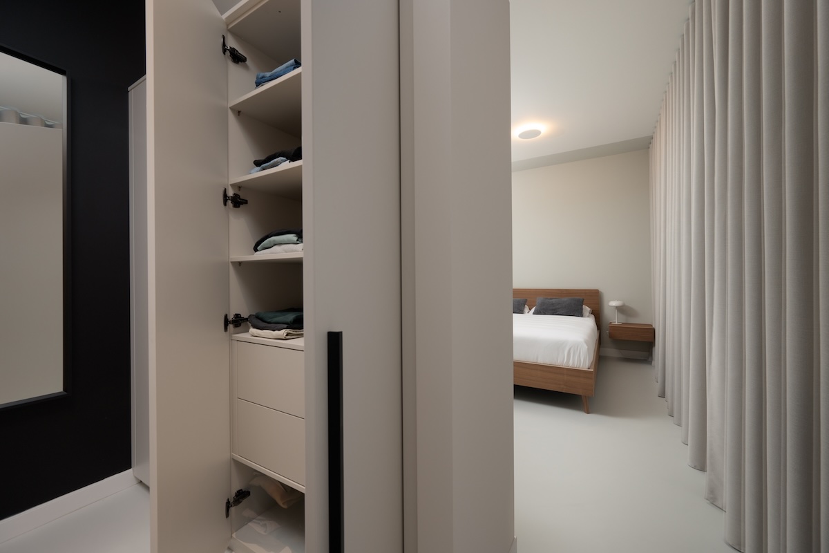 Slaapkamer met houten design bed en op maat gemaakte inloopkast