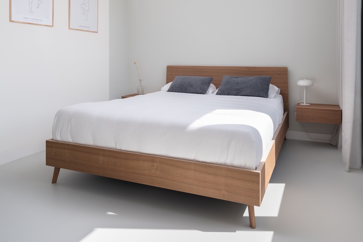 Detail van houten bed in moderne slaapkamer met inloopkast